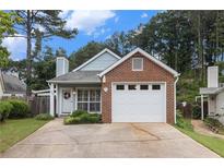 Charming single-story home featuring a brick facade, attached garage, and well-manicured front yard at 1908 Brittania Cir, Woodstock, GA 30188