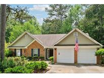 Charming one-story brick home featuring an attached two-car garage and lush, mature landscaping at 2080 Bankston Cir, Snellville, GA 30078