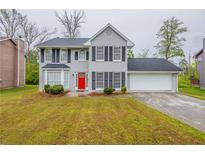 Charming two-story home featuring a well-manicured lawn, classic shutters, and a vibrant red front door at 6590 Smoke Ridge Dr, Atlanta, GA 30349