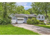 Charming home featuring a blue exterior, attached garage, and a driveway, surrounded by mature trees at 3551 Cindy Way, Rex, GA 30273