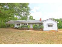 Charming single story home featuring a front porch and established landscaping in a lush green setting at 6191 Cumming Hwy, Canton, GA 30115