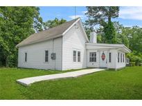 Charming cottage-style home featuring white siding and a well-manicured front lawn at 6802 Ida St, Lithonia, GA 30058