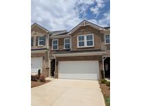 Brick townhome exterior with a two-car garage and well-manicured landscaping for a polished look at 934 Elwood St, Dacula, GA 30019