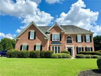 Beautiful two-story brick home featuring a well-manicured lawn, black shutters, and a classic design at 1805 Hunters Moon Dr, Alpharetta, GA 30005
