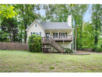 Charming home with a wooden porch and stairs, surrounded by lush greenery and a picket fence at 3021 Mills Ridge Dr, Canton, GA 30114