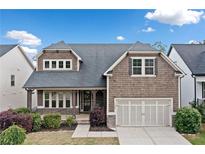 Charming two-story home with shake siding, covered porch, a two-car garage and well-manicured landscaping at 322 Woodridge Pass, Canton, GA 30114