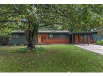 Charming single-story home featuring a well-manicured lawn and mature trees with a brick accent and cheerful orange front door at 3580 Raymond Dr, Atlanta, GA 30340