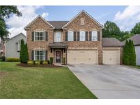 Stately two-story brick home with a three-car garage, well-maintained lawn, and mature landscaping at 4305 Hunters Walk Way, Cumming, GA 30028
