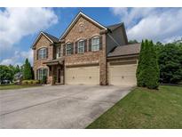 Stunning brick two-story home with a three-car garage and well-manicured lawn at 4305 Hunters Walk Way, Cumming, GA 30028