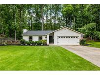 Charming single-story home featuring a lush green lawn, manicured landscaping, and an attached two-car garage at 171 North Trce, Alpharetta, GA 30009