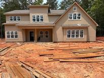 Two-story home featuring beige siding and multiple windows, set against a backdrop of lush trees at 7947 Post Rd, Winston, GA 30187