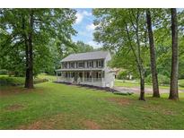 Charming two-story home with a welcoming front porch and beautifully landscaped yard, surrounded by mature trees at 1925 Stonewyck Ct, Cumming, GA 30041