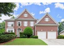 Charming two-story brick home featuring a well-manicured lawn, a two-car garage, and mature landscaping at 4108 Wyndam Hill Dr, Suwanee, GA 30024