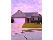 Charming single-story brick home featuring a two-car garage and manicured front lawn at 942 Village View Cir, Loganville, GA 30052