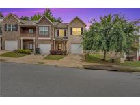 Charming townhome showcasing brick facade, attached garages, and a beautifully landscaped front yard at 10151 Benton Woods Dr, Covington, GA 30014