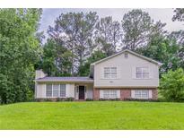 Charming two-story home with a well-manicured lawn and lush surrounding trees at 803 Cedar Lake Se Dr, Conyers, GA 30094