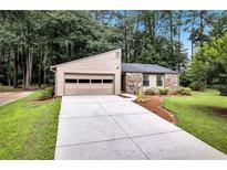 Charming single-story home featuring stone accents, an attached garage, and a well-maintained front yard at 2786 Olde Gate Ct, Snellville, GA 30078