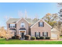Traditional brick home featuring a manicured lawn, mature landscaping, and an attached two-car garage at 122 Melrose Creek Dr, Stockbridge, GA 30281