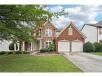 Charming two-story brick home features a manicured lawn, a two-car garage, and mature shade trees at 251 Sumac Trl, Woodstock, GA 30188