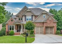 Charming two-story home with a well-manicured lawn, stone and brick facade, and two-car garage at 3150 Seven Oaks Dr, Cumming, GA 30041