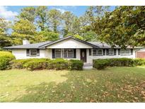 Charming, single-story home with white brick, black trim, and mature landscaping at 6873 Church St, Riverdale, GA 30274