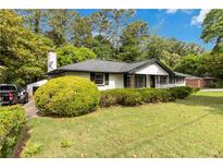 Charming one-story home with a manicured front lawn, mature landscaping, and whitewashed brick exterior at 6873 Church St, Riverdale, GA 30274