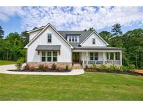 Charming two-story home featuring white board and batten siding, stone accents, and a welcoming front porch at 130 Lapis Lake Point Pt, Fayetteville, GA 30215