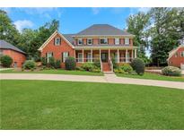 Charming two-story brick home with a large front lawn, covered porch, and manicured landscaping at 2535 Winthrope Way, Lawrenceville, GA 30044