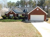 Charming brick home with a well-manicured lawn, lush landscaping, and a two-car garage at 40 Pebble Brooke Ct, Covington, GA 30016