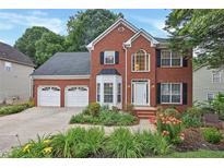 Charming brick home featuring a two-car garage, manicured landscaping, and a welcoming front entrance at 2018 Township Dr, Woodstock, GA 30189