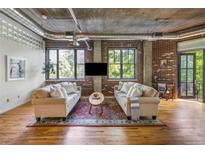 Open living room with hardwood floors, brick walls, and large windows offering plenty of natural light at 3235 Roswell Ne Rd # 505, Atlanta, GA 30305