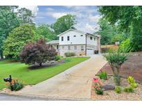 Charming two-story home with a well-maintained lawn, landscaped yard, and a long driveway leading to a garage at 281 Lakeshore Ne Dr, Marietta, GA 30067