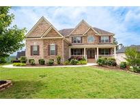 Beautiful two-story brick home with a manicured front lawn and covered entryway at 6585 Canyon Cv, Cumming, GA 30028