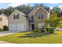 Charming two-story home with stone accents, a two-car garage, and manicured lawn at 211 Millstone Dr, Hampton, GA 30228