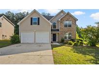 Charming two-story home with stone accents, manicured lawn, and a two-car garage at 211 Millstone Dr, Hampton, GA 30228