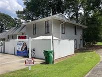 View of exterior featuring a two-story design with siding, white fence, open house sign, and lush greenery at 4312 Idlewood Ln, Tucker, GA 30084