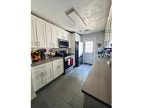 Galley kitchen featuring white cabinets, grey tile flooring, and stainless steel appliances at 4312 Idlewood Ln, Tucker, GA 30084