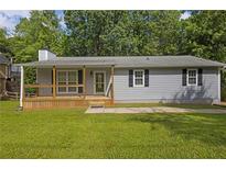 Charming single-story home with a light gray exterior and a welcoming front porch surrounded by lush greenery at 4070 Feather Dr, Douglasville, GA 30135