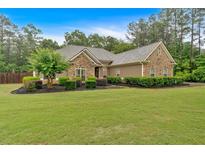 Well-maintained single-story home with stone accents, manicured landscaping, and lush green lawn at 7030 Mandevilla Ln, Douglasville, GA 30135