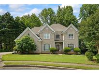 Charming brick home featuring manicured lawn and mature trees, enhancing its curb appeal at 2700 Still Farms Ct, Lawrenceville, GA 30043