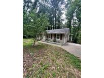 Charming single story home with neutral siding and red shutters surrounded by mature trees and a front yard at 2708 Beacon Dr, Atlanta, GA 30360