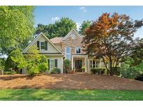 Charming home showcasing a stone and siding facade, well-manicured lawn and a mature landscape at 4750 Freeport Bay Ne, Roswell, GA 30075