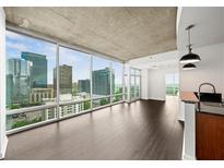 Bright living room with floor-to-ceiling windows offering a beautiful city view and sleek hardwood floors at 943 Peachtree Ne St # 1518, Atlanta, GA 30309