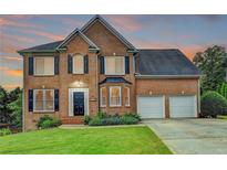 Charming two-story brick home with a well-manicured lawn and a two-car garage, located in a suburban neighborhood at 3760 Ansley Park Dr, Suwanee, GA 30024