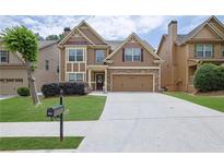 Inviting two-story home featuring a stone accents, a two-car garage, and a well-manicured front lawn at 1267 Castleberry Dr, Buford, GA 30518
