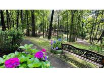 Inviting garden path featuring colorful flowers and a quaint bench, surrounded by lush greenery and mature trees at 2985 Heather Stone Way, Lawrenceville, GA 30043