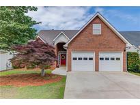 Charming brick home featuring a two-car garage, well-manicured lawn, and inviting red front door at 3585 Berkeley Park Ct, Duluth, GA 30096