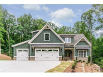 Charming home showcasing a welcoming three-car garage and a beautifully landscaped front yard at 7080 Driskell Cir, Cumming, GA 30041