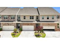 Charming townhome exteriors with brick and stone accents and two-car garages at 2340 Manor Pointe Dr, Cumming, GA 30041