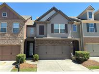 Two-story townhouse with a two-car garage, neat landscaping, and stone and siding exterior at 2351 Attewood Dr, Buford, GA 30519